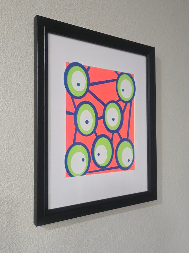 Framed abstract artwork with geometric design on a wall.
